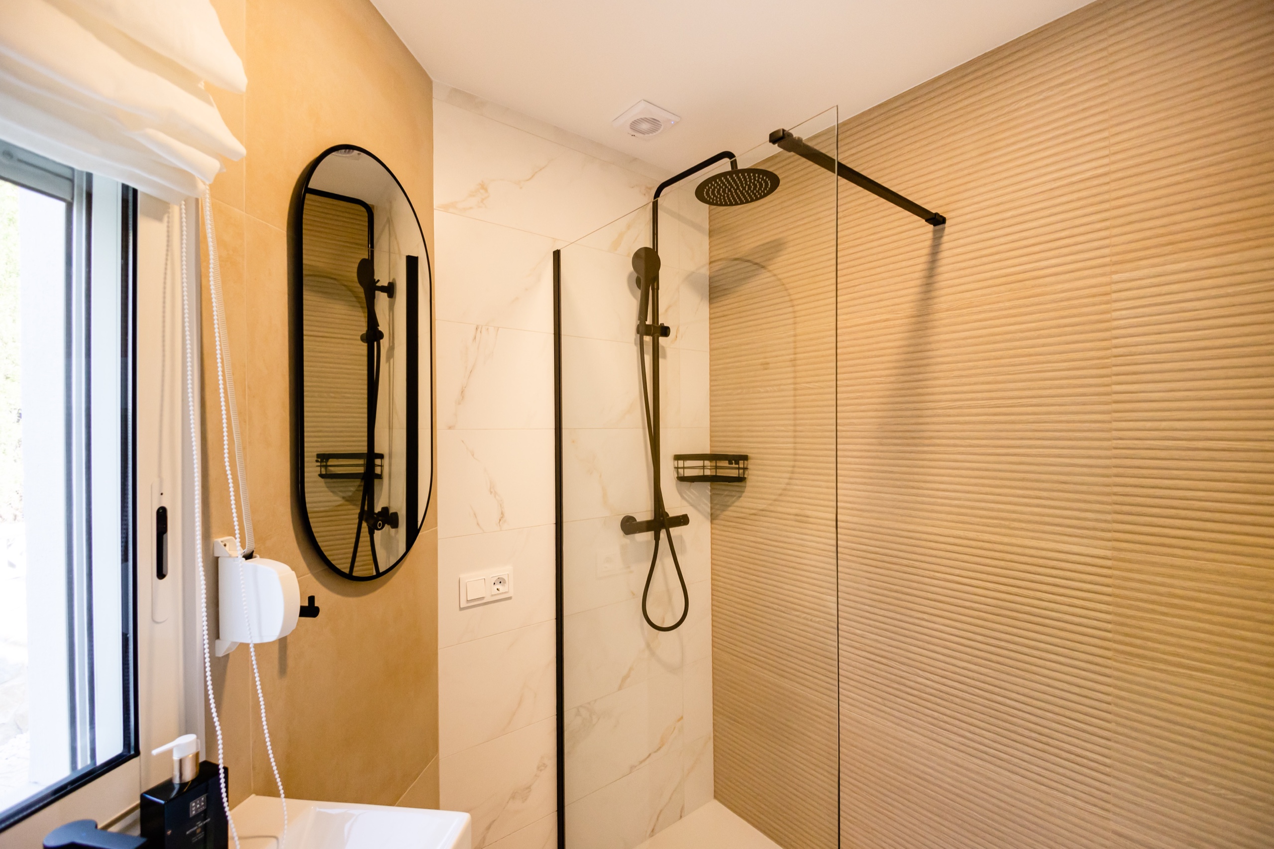 Glass shower with black fittings and ribbed stone tiles