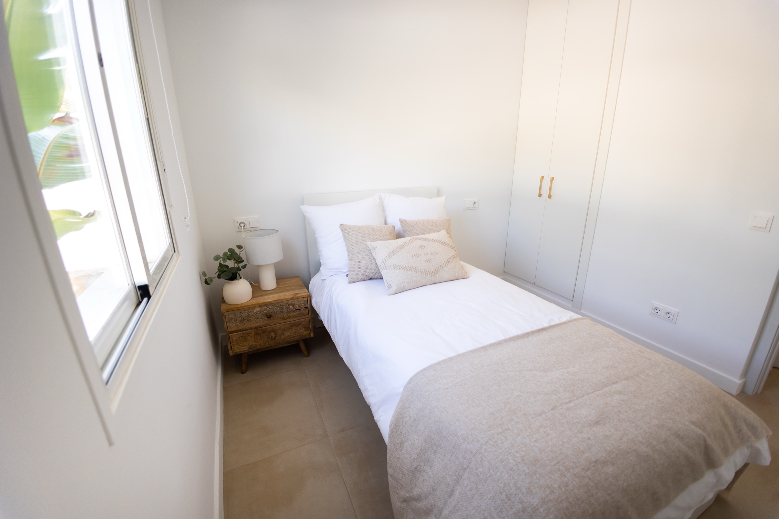 Bedroom with a single bed, carved nightstand, and white wardrobe