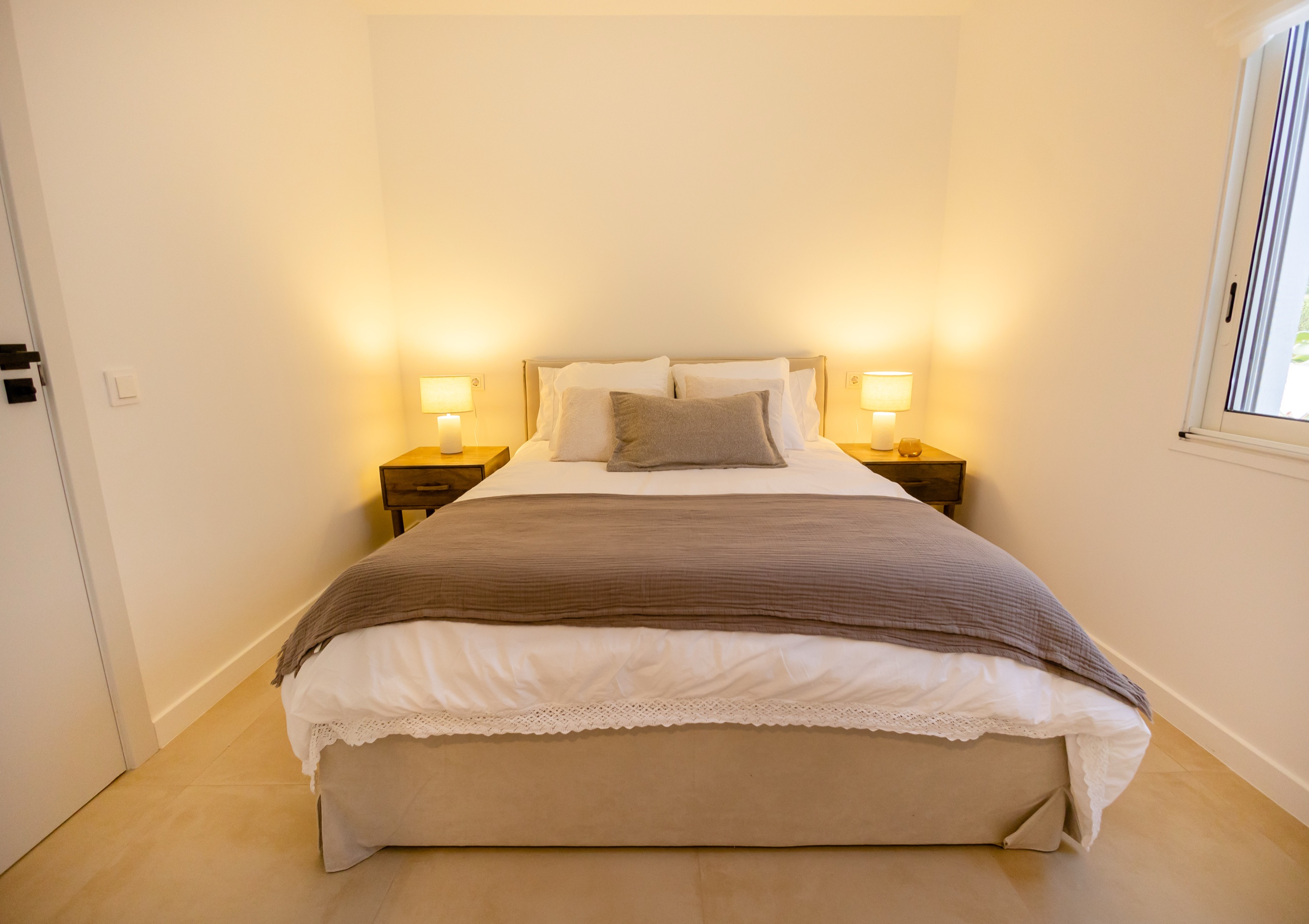 Bedroom with lamps on oak nightstands and a taupe throw