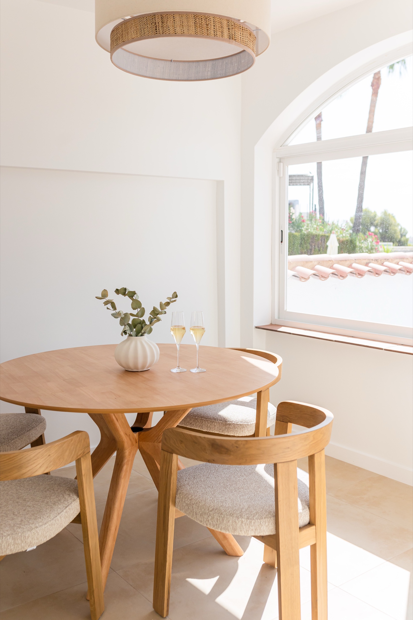 Round oak dining table with glasses by the arched window