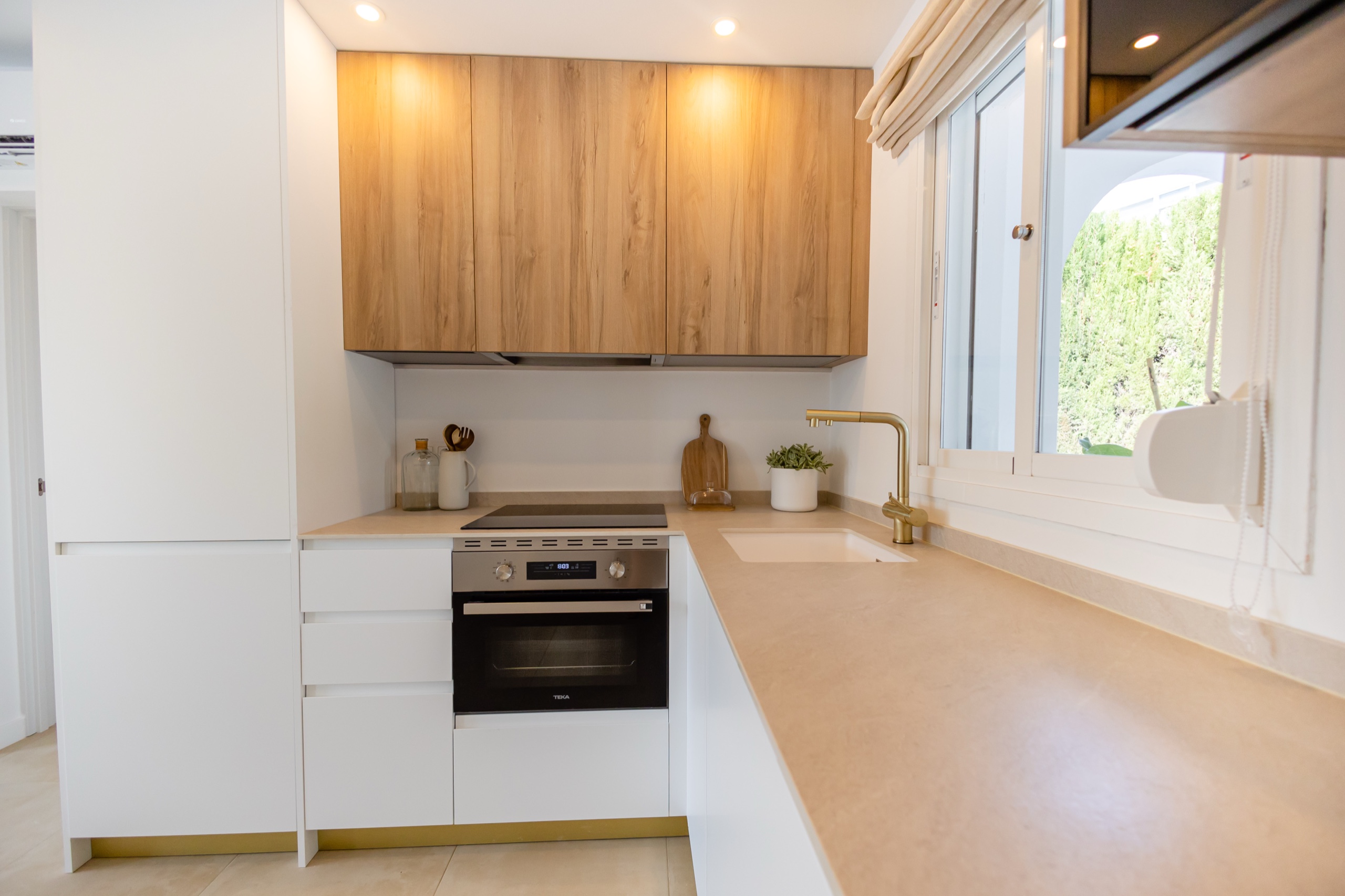 Kitchen worktop with oak uppers, hob, oven, and a brass tap