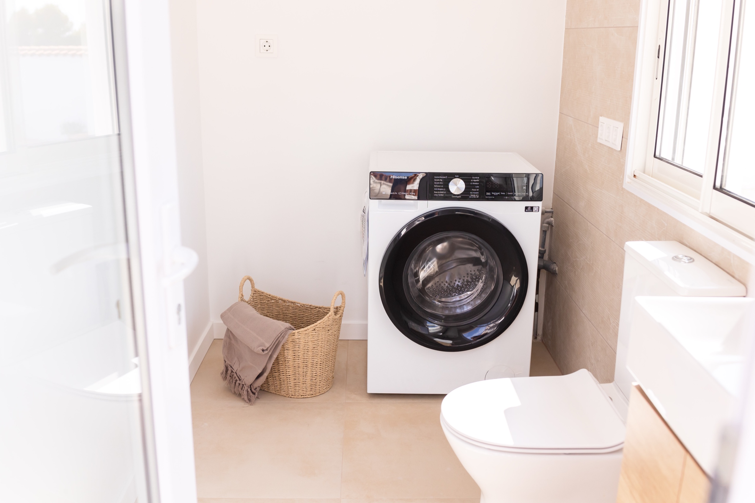 Laundry alcove with a washing machine, basket, and window light
