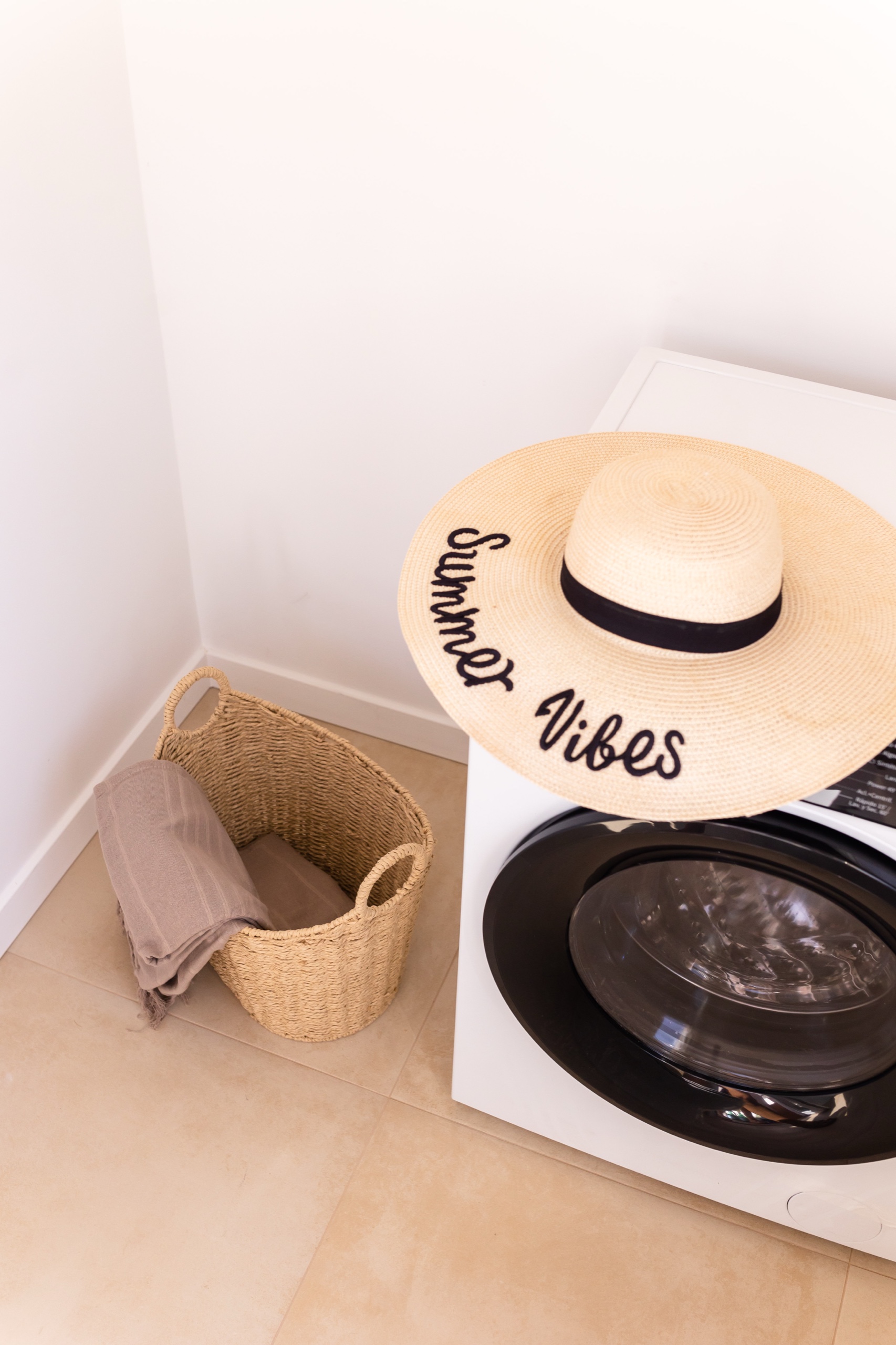 Straw hat on the washing machine beside a wicker laundry basket